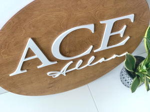 3D round wooden name sign with white raised block letters ACE and cursive Allan on natural wood background