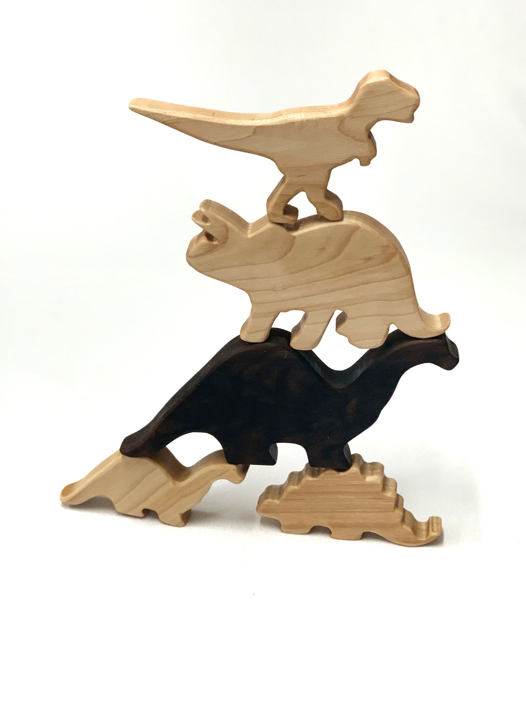 Natural wooden dinosaur toy figurines stacked in balanced pile on white background