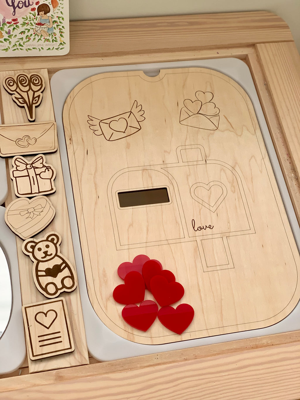 Set of seven red acrylic heart shapes on wooden tray with engraved mailbox and love-themed illustrations