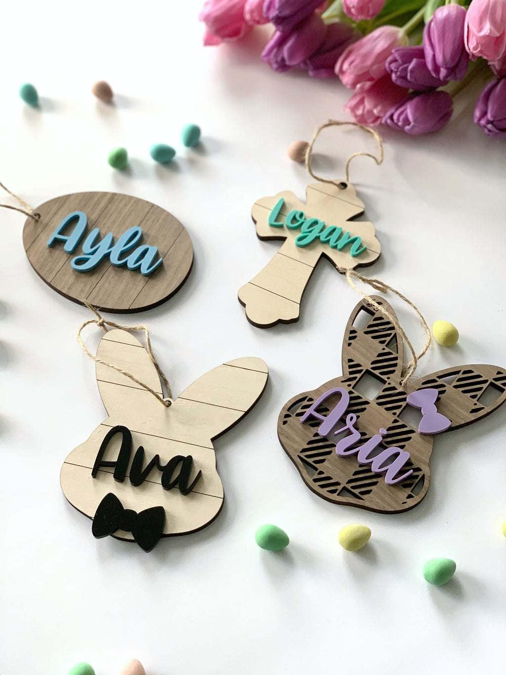 Custom wooden Easter basket name tags with pastel-colored names in script and bunny and cross shapes on light wood background