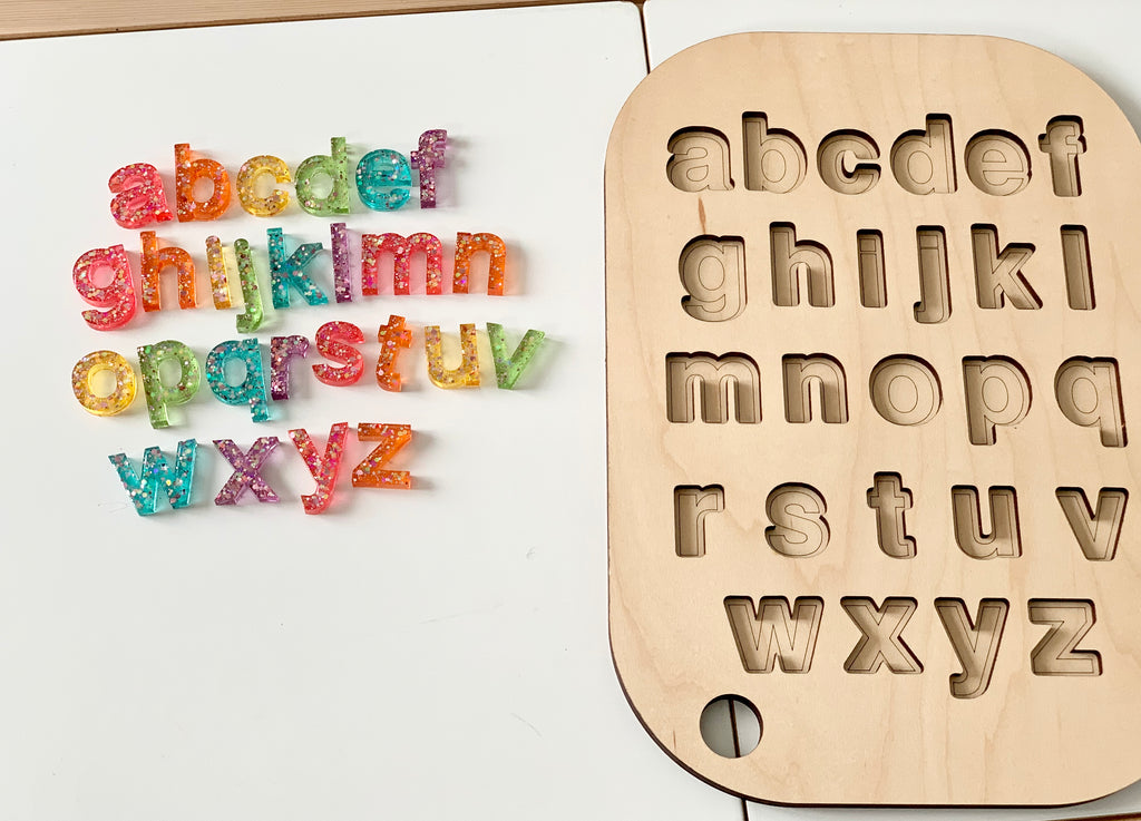 Wooden Flisat table top insert with lowercase alphabet letter cutouts and colorful resin letters on white surface