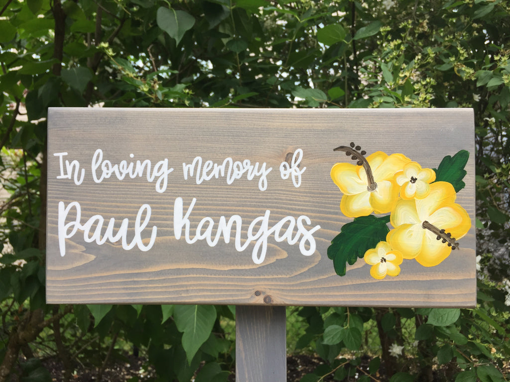 Personalized wooden memorial garden sign painted gray with white script letters and yellow floral illustration on natural wood grain