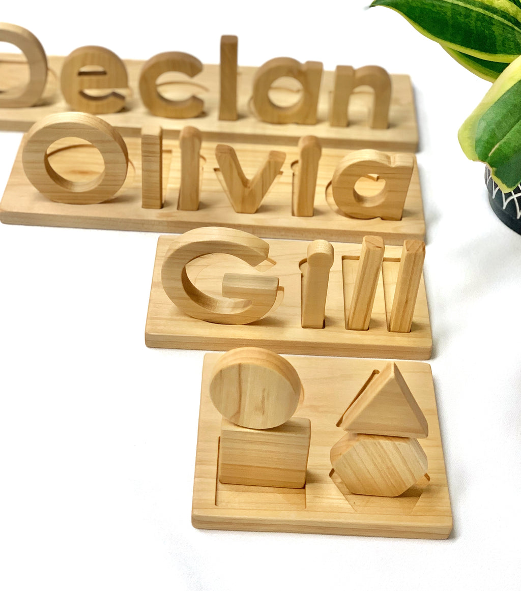 Natural wooden name puzzles with engraved letters Declan Olivia Gill and a basic wooden shape puzzle on white surface
