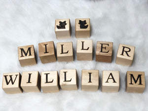 Natural wooden 1.5 inch alphabet blocks with engraved capital letters and animal illustrations on white textured background