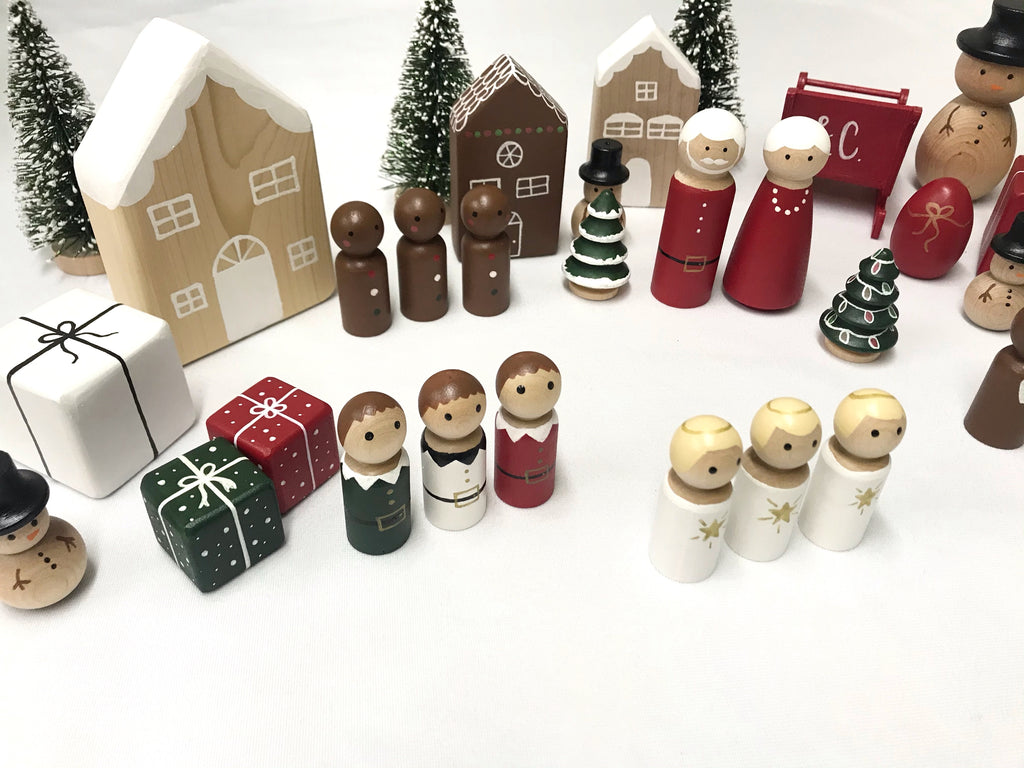 Collection of hand-painted wooden Christmas peg dolls and festive decorations on white background