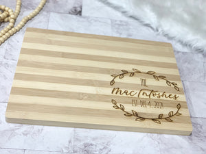 Natural striped bamboo serving board with personalized engraved wreath and custom name and date design on corner