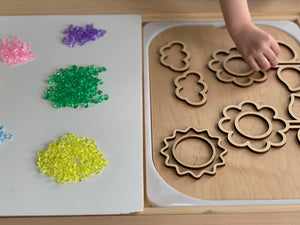 Assorted mini acrylic treasure gems in yellow, green, purple, pink, and blue next to wooden flower and cloud puzzle pieces on table