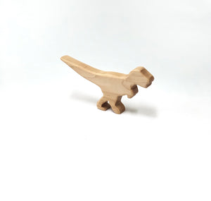 Small natural wooden dinosaur toy figurine with simple carved details on white background