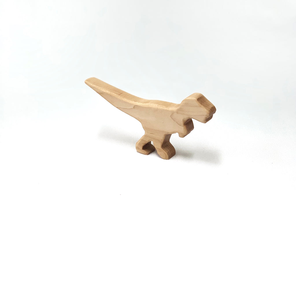 Small natural wooden dinosaur toy figurine with simple carved details on white background