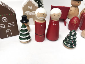 Set of handcrafted wooden Christmas peg dolls including Santa, Mrs. Claus, gingerbread house, trees, and festive decorations