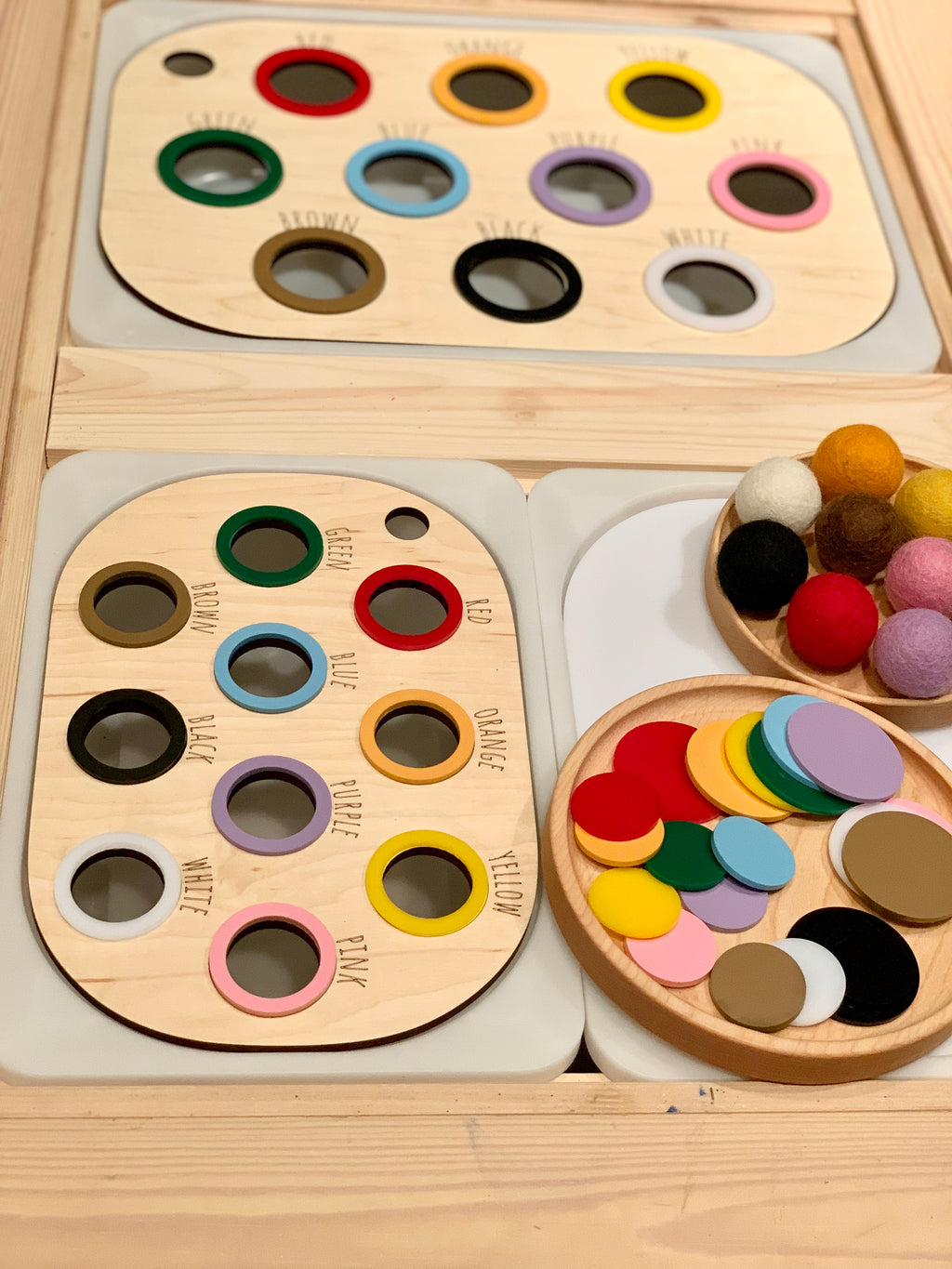Wooden colour sorting Flisat table bin lids with labelled holes and colorful felt balls and discs on natural wood surface